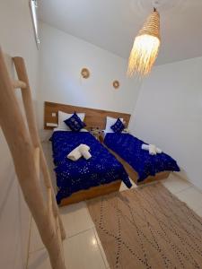 a bedroom with two beds with blue sheets and a chandelier at Essaouira Stay with private Terrace in Essaouira +44 photos