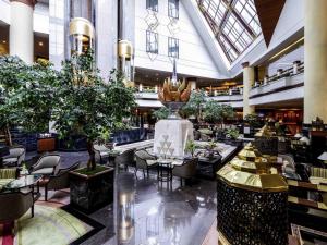 a lobby with tables and chairs in a building at Pullman Khon Kaen Raja Orchid in Khon Kaen