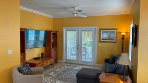 a living room with yellow walls and a ceiling fan at Coral Garden by AvantStay Great Location w Balcony Shared Pool in Stock Island