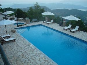 a large blue swimming pool with chairs and umbrellas at Merlot Village Rental Properties in Kariá