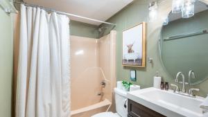a bathroom with a sink and a toilet and a mirror at Lakeshore Oasis by AvantStay Private Beach Views Hot Tub Volleyball in Blakeslee +49 photos