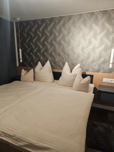 Elle comprend un grand lit avec des draps et des oreillers blancs. dans l'établissement Costyn Apartments 1, à NuÃŸbaum