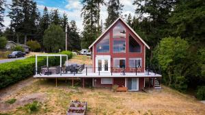 a small house with a large deck on a field at Polnell Point Lookout by AvantStay Water Views Hot Tub Large Patio in Oak Harbor