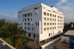 a white building with a palm tree in front of it at Royal Park Kakinada in Kākināda
