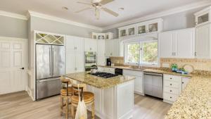 a kitchen with white cabinets and a kitchen island with stools at Hilton Ivory 15th Hole of Harbourtown Golf Course Private Pool Hot Tub in Hilton Head Island