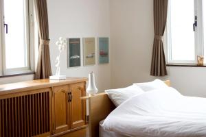 a bedroom with a bed with white sheets and windows at Seaside Inn Hokuto in Hokuto