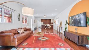a living room with a brown couch and a red rug at Southwest by AvantStay Heart of Hollywood Remodeled 1920s Bungalow in Los Angeles