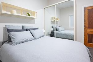 a white bedroom with a bed and a mirror at Prime City to Coast Locale in Plympton
