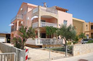 a house with a balcony and a dog on top of it at Apartments Vidolma in Povljana