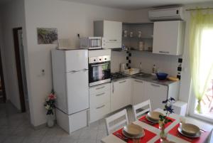 a kitchen with a white refrigerator and a table with chairs at Apartments Vidolma in Povljana