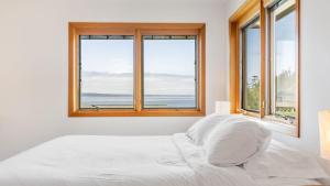 una camera da letto bianca con finestre e un letto con lenzuola bianche di The Majestic Blue View by AvantStay Waterfront a Freeland