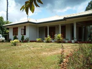 a white house with plants in a yard at Samanala Holiday Resort in Bandarawela