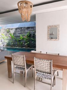 a dining room with a wooden table and two chairs at Mai Villa Umalas in Canggu