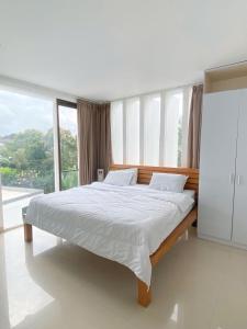 a bedroom with a white bed with a large window at Mai Villa Umalas in Canggu