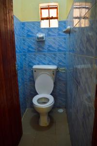 uma casa de banho com um WC e uma parede de azulejos azuis em Saboti Hotel em Mai Mahiu