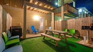a patio with a wooden table and green chairs at The Beautiful Place by AvantStay Mins to Beach Family-Friendly Pool in Padre Island
