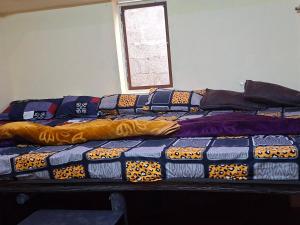 a pile of blankets and pillows on a bed at Dadysmud house in Kottakamboor