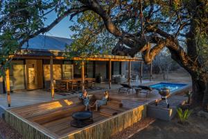 a house with a wooden deck and a tree at Nomads Den Safari Villas - Heated Pools and Riverbed views in Hoedspruit