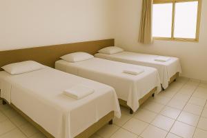 a room with three beds and a window at ECONÔMICA AR ESTACIONAMENTO e CAFÉ in Canoas