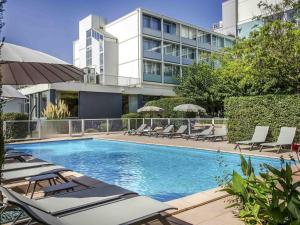 ein Swimmingpool mit Liegestühlen und ein Gebäude in der Unterkunft Ibis Cavaillon Portes du Luberon in Cavaillon