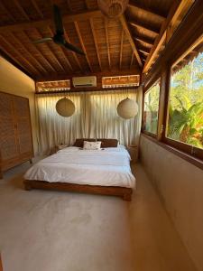 Un dormitorio con una cama en una habitación con ventanas. en JADA - New Quiet & Cozy House with Balinese Charm, en Bingin Beach