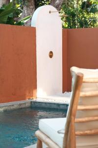 Una silla junto a una piscina con puerta. en JADA - New Quiet & Cozy House with Balinese Charm, en Bingin Beach