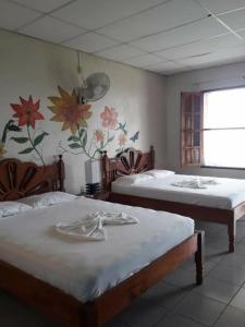 two beds in a room with flowers on the wall at El Mirador Ecológico, Ometepe in Altagracia