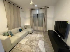a living room with a white couch and a flat screen tv at Dee s Home in Dar es Salaam