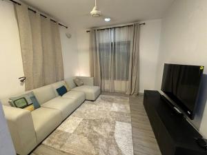 a living room with a white couch and a flat screen tv at Dee s Home in Dar es Salaam +1 photo