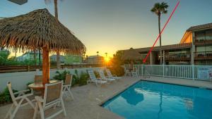 a resort with a pool with chairs and a straw umbrella at Beach Boardwalk Access Pool Remodeled Interior Tropical Haven by AvantStay in Port Aransas