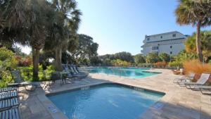 a large swimming pool with chairs and a building at 401 A Shipwatch by AvantStay Beachfront Condo w Community Pool Access in Isle of Palms