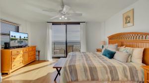 a bedroom with a bed and a television and a balcony at 401 A Shipwatch by AvantStay Beachfront Condo w Community Pool Access in Isle of Palms +29 photos