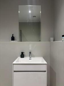 a white bathroom with a sink and a mirror at Studio in Woodstock in Cape Town