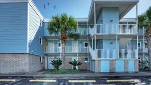 a building with palm trees in front of it at Sleeps 18 2 Beachfront Condos w 2 Pools TennisPickleball Beach Boardwalk in Port Aransas