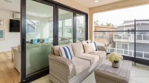 ein Wohnzimmer mit Couch und Balkon in der Unterkunft Velvet Sand I by AvantStay Steps to Newport Beach Private Rooftop w Outdoor Kitchen Hot Tub in Newport Beach