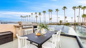 ein Tisch auf einem Balkon mit Grill und Palmen in der Unterkunft Velvet Sand I by AvantStay Steps to Newport Beach Private Rooftop w Outdoor Kitchen Hot Tub in Newport Beach