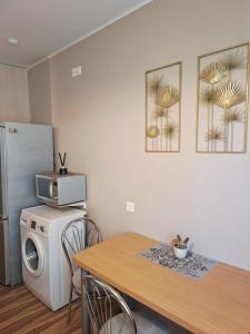 a small kitchen with a table and a refrigerator at Klaipėda Apartament in Klaipėda
