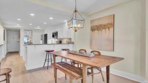 a kitchen and dining room with a wooden table and chairs at 303A Shipwatch by AvantStay Ocean View Shared Pool Boardwalk to Beach in Isle of Palms