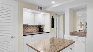 a kitchen with white cabinets and a granite counter top at 303A Shipwatch by AvantStay Ocean View Shared Pool Boardwalk to Beach in Isle of Palms +18 photos