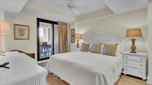 a white bedroom with two beds and a window at 303A Shipwatch by AvantStay Ocean View Shared Pool Boardwalk to Beach in Isle of Palms