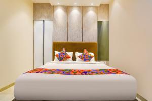 a bedroom with a large white bed with colorful pillows at Fabhotel Nexus Inn near Nesco in Mumbai