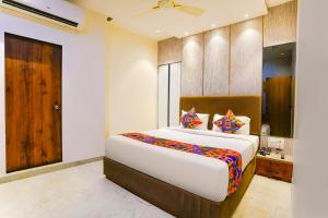 a bedroom with a large bed and a wooden door at Fabhotel Nexus Inn near Nesco in Mumbai