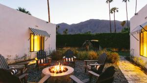 eine Terrasse mit Stühlen, einem Tisch und einer Feuerstelle in der Unterkunft The EL Cid Buyout by AvantStay in Palm Springs