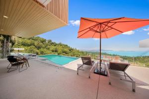 a patio with an umbrella and chairs and a pool at Villa Fanta Sea - Luxury Residence at Chaweng Noi in Koh Samui 