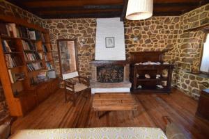 a living room with a fireplace and a stone wall at Eftopia Martino Pansion in Martínon