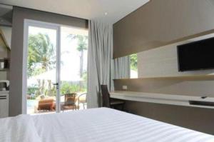 a bedroom with a white bed and a large window at Double G Resort Anyer in Babagan +98 photos