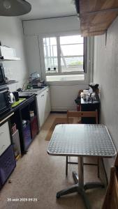 CourcouronnesにあるChambre 1 Personneの部屋の中央にテーブルがあるキッチン +2枚の写真