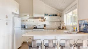 una cucina con elettrodomestici bianchi e bancone con sgabelli di Cozy Whidbey Island Stay Steps on the beach Fireplace BBQ Near Trails a Freeland Altre 19 foto