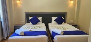 two beds with blue and white pillows in a room at Seaside Dhangethi Inn in Dhangethi