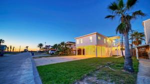 a house with a palm tree next to a street at Priv Pool Yard w Putting Green Newly Remodeled Always Sunny by AvantStay in Port Aransas